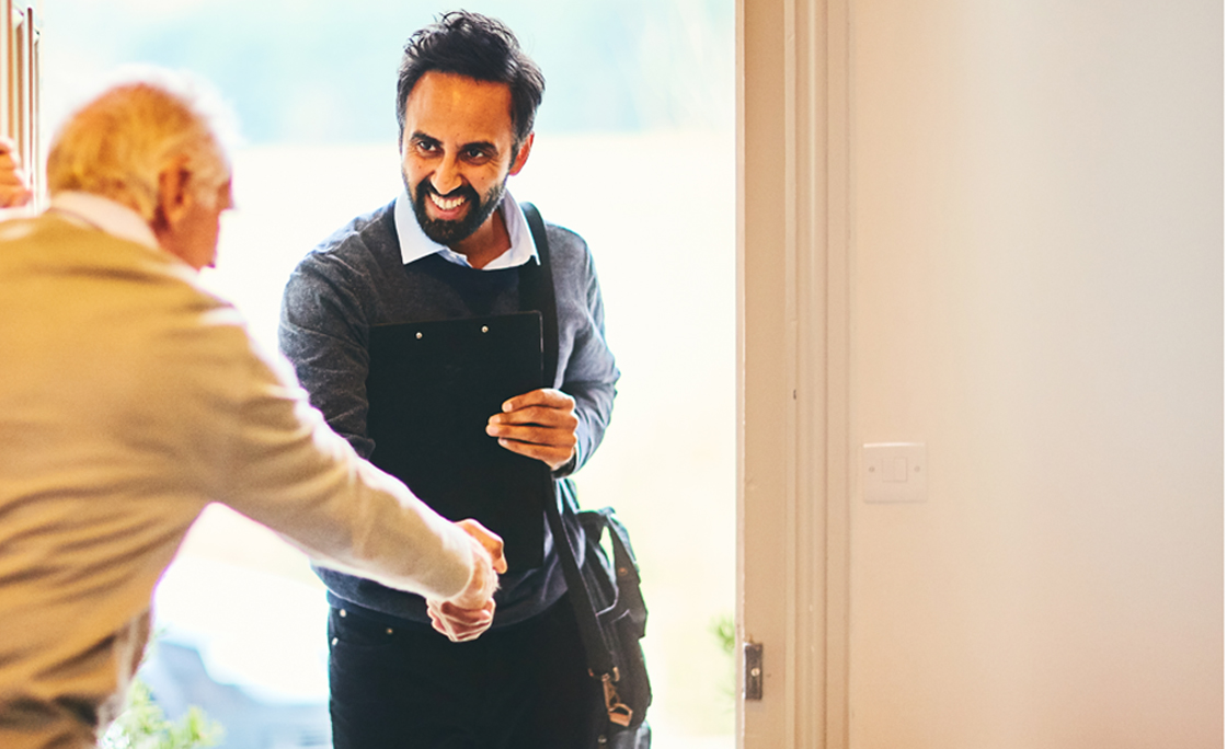 Senior man welcoming a healthcare worker – Home visit