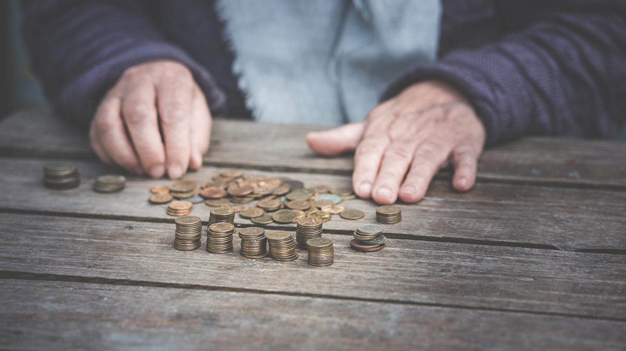 wrinkled hands of the old woman touch coins on a wooden table