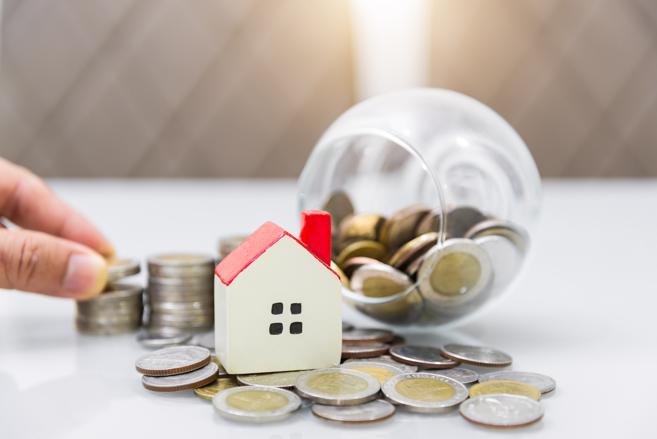 Property investment and house mortgage financial concept, Hand putting money coin stack with wooden house