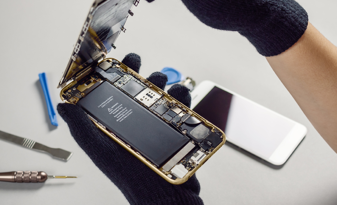 Technician repairing broken smartphone on desk