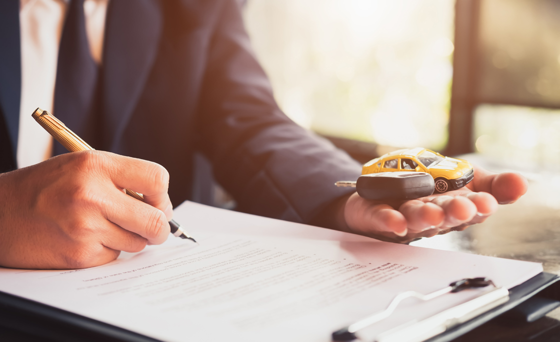 Midsection Of Car Insurance Agent Writing On Form While Holding Key At Office