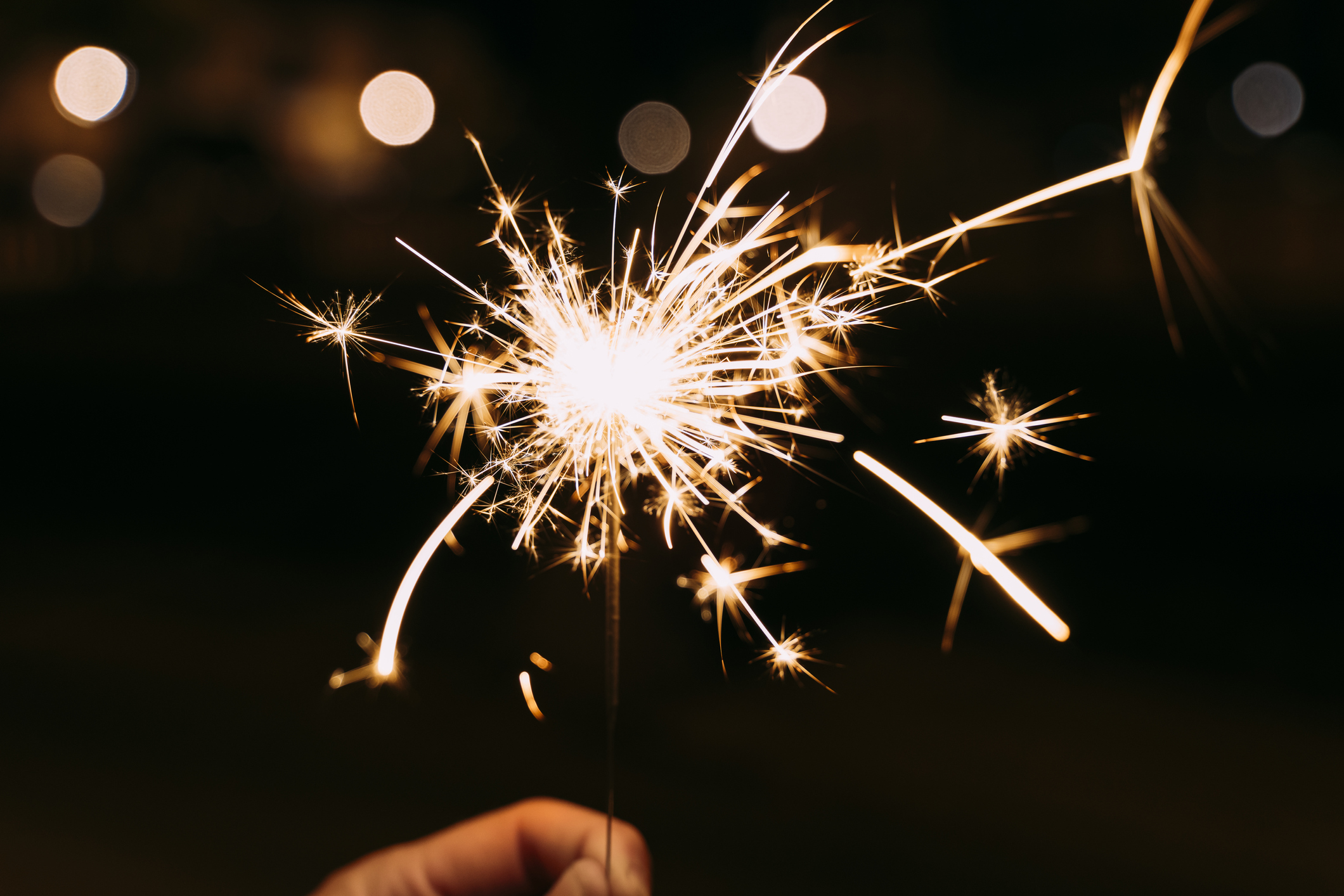 Hand holding a burning sparkler at a party