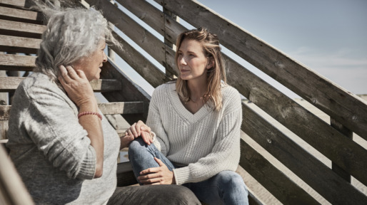 Senior woman talking with adult daughter on footbridge at the beach