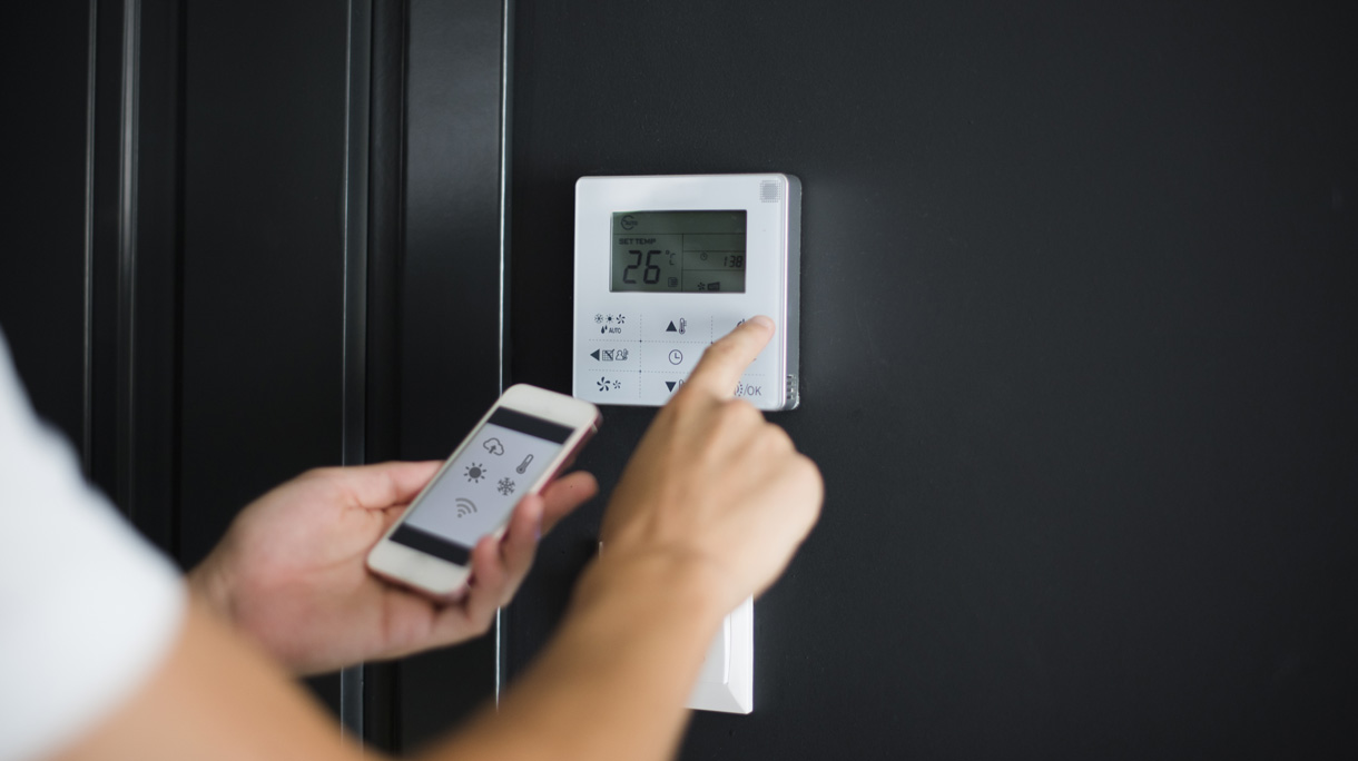Close up of man using smart phone app to adjusting digital thermostat