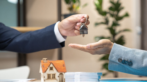Estate agent giving house keys to woman and sign agreement in office
