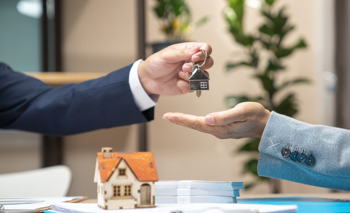 Estate agent giving house keys to woman and sign agreement in office