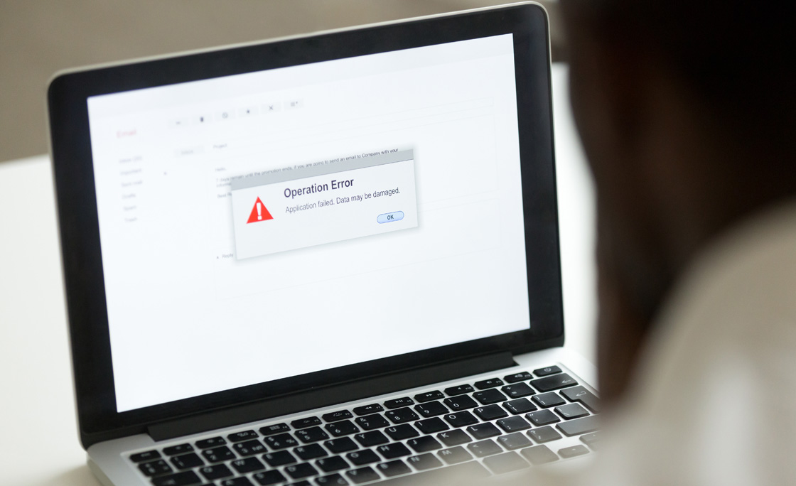 African man using laptop with application failure message on screen