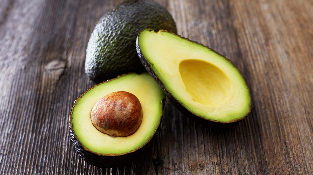 Whole and sliced avocado on wood