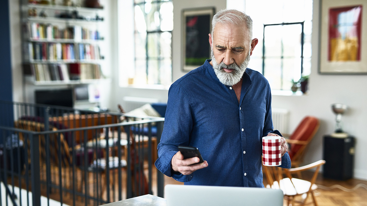 Senior creative professional remote working and checking phone at home