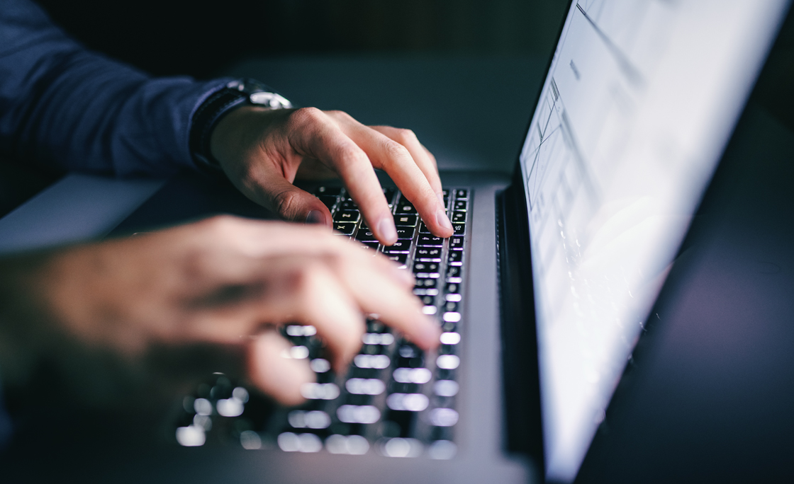 Close up of hands typing on laptop. Night work concept.