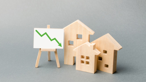 Wooden houses and an easel arrow down. The fall of the real estate market. concept of value or cost decrease. low liquidity and attractiveness. cheap rent. Reduced demand and market stagnation.