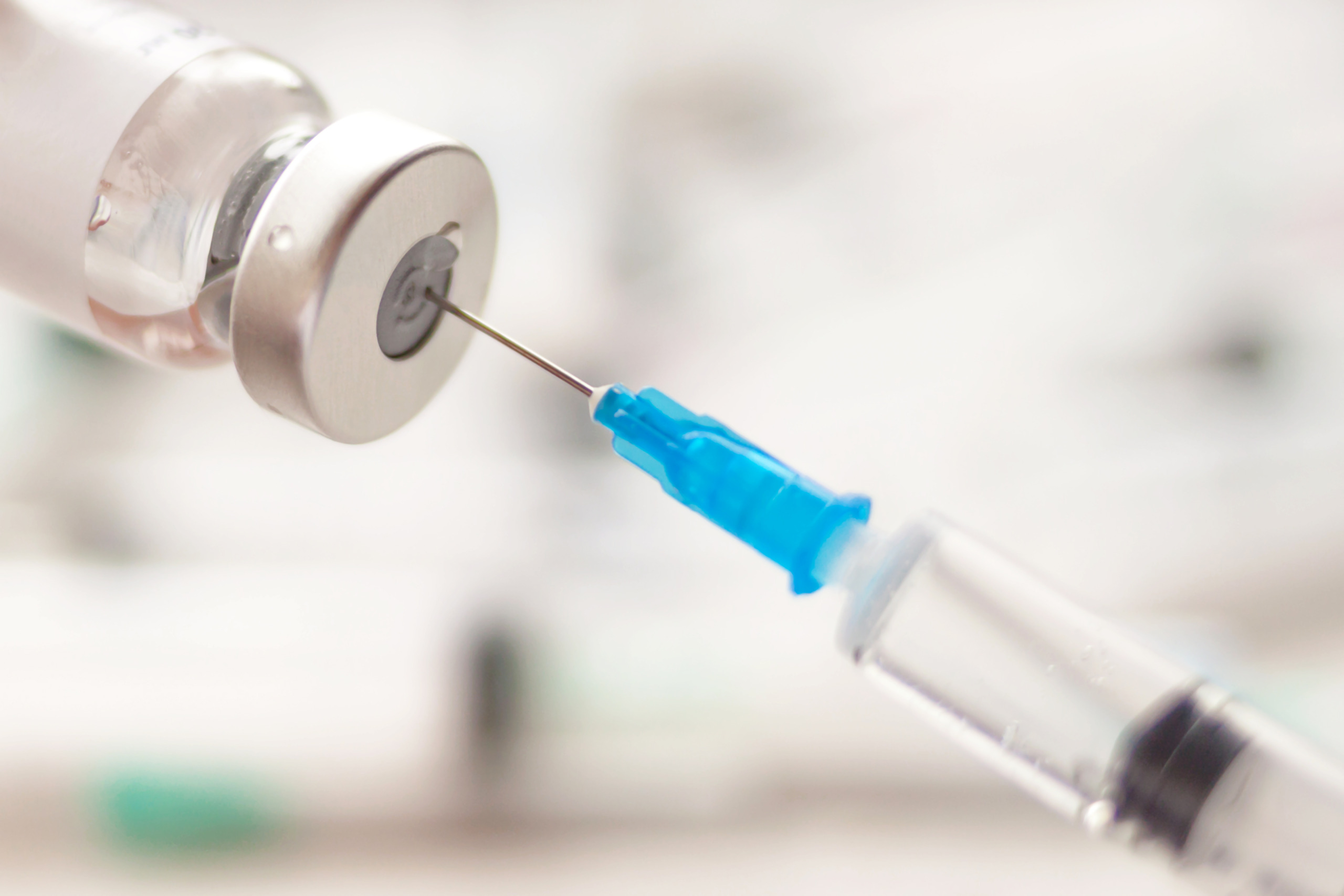Dialing medicine into syringe from glass bottle. Ampoule and syringe needle close-up.