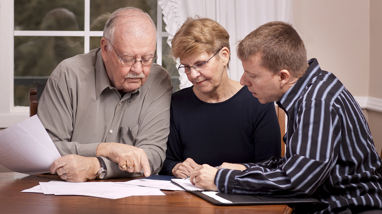 Financial advisor with senior couple going over paperwork