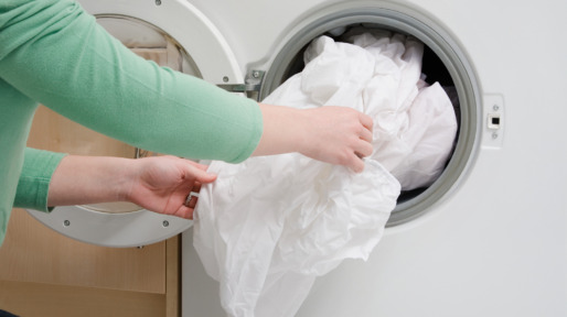 Woman taking sheet from washing machine