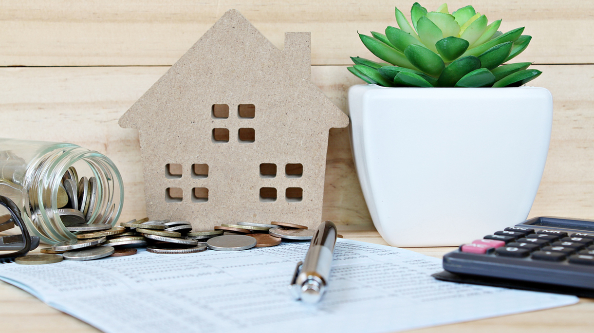 Wood house mode, coins scattered from glass jar, calculator on saving account passbook or financial statement