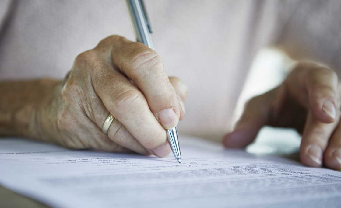 Senior woman’s hand signing a document, close-up