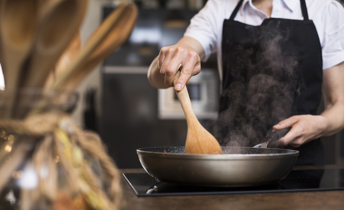 Close-up of woman cooking in kitchen using a pan