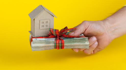 concept of buying an apartment, a hand holding a stack of Polish banknotes with a paper house model