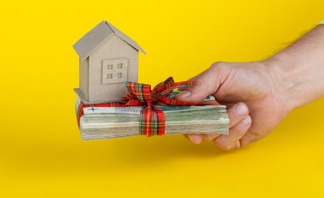 concept of buying an apartment, a hand holding a stack of Polish banknotes with a paper house model