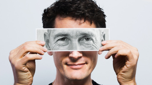 Young man holding picture of old eyes over his