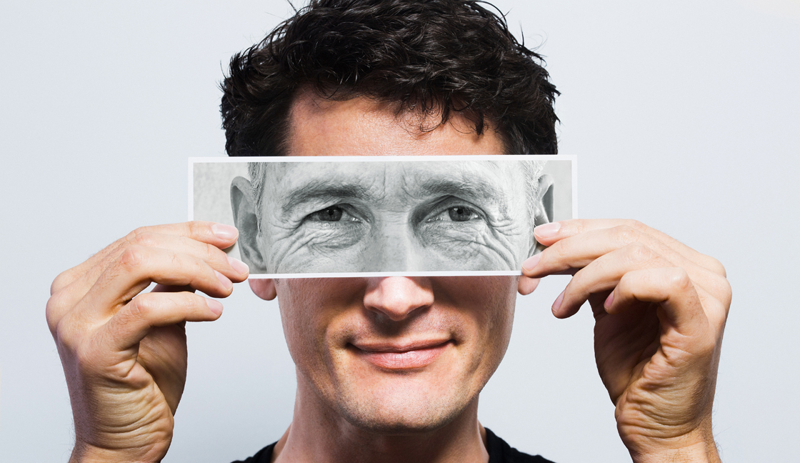 Young man holding picture of old eyes over his