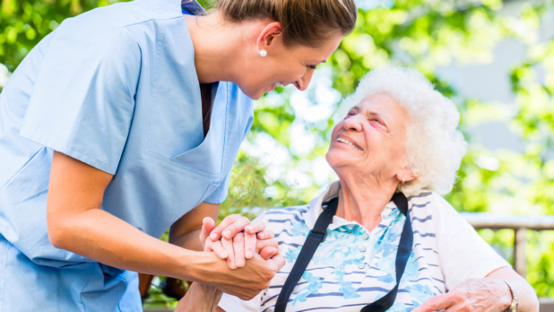 Nurse holding hand of senior woman in pension home