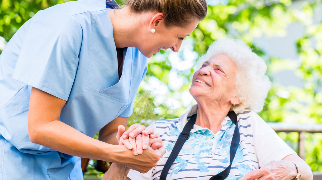 Nurse holding hand of senior woman in pension home