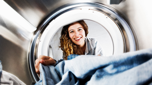 Smiling blonde beauty loads her tumble dryer: seens from inside