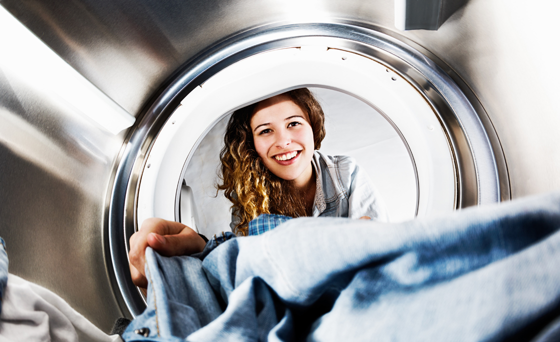 Smiling blonde beauty loads her tumble dryer: seens from inside