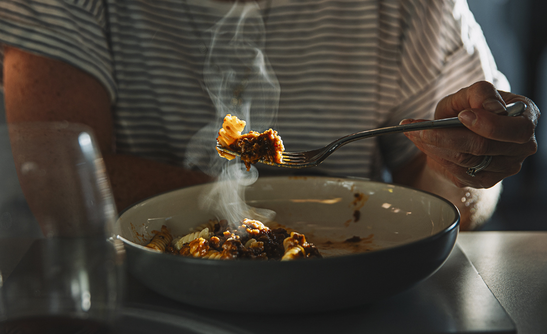 Woman eating fusilli pasta with bolognese sauce