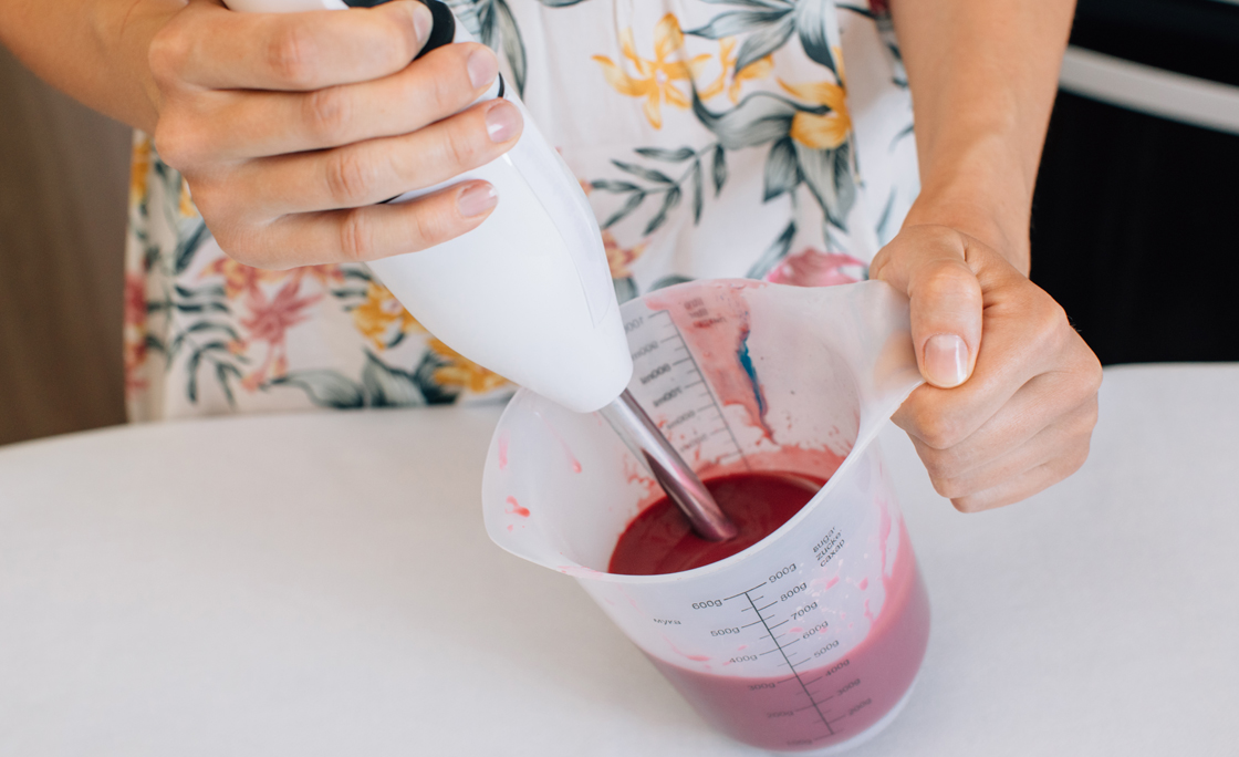 Close-up of a woman mixing icing with a hand blender