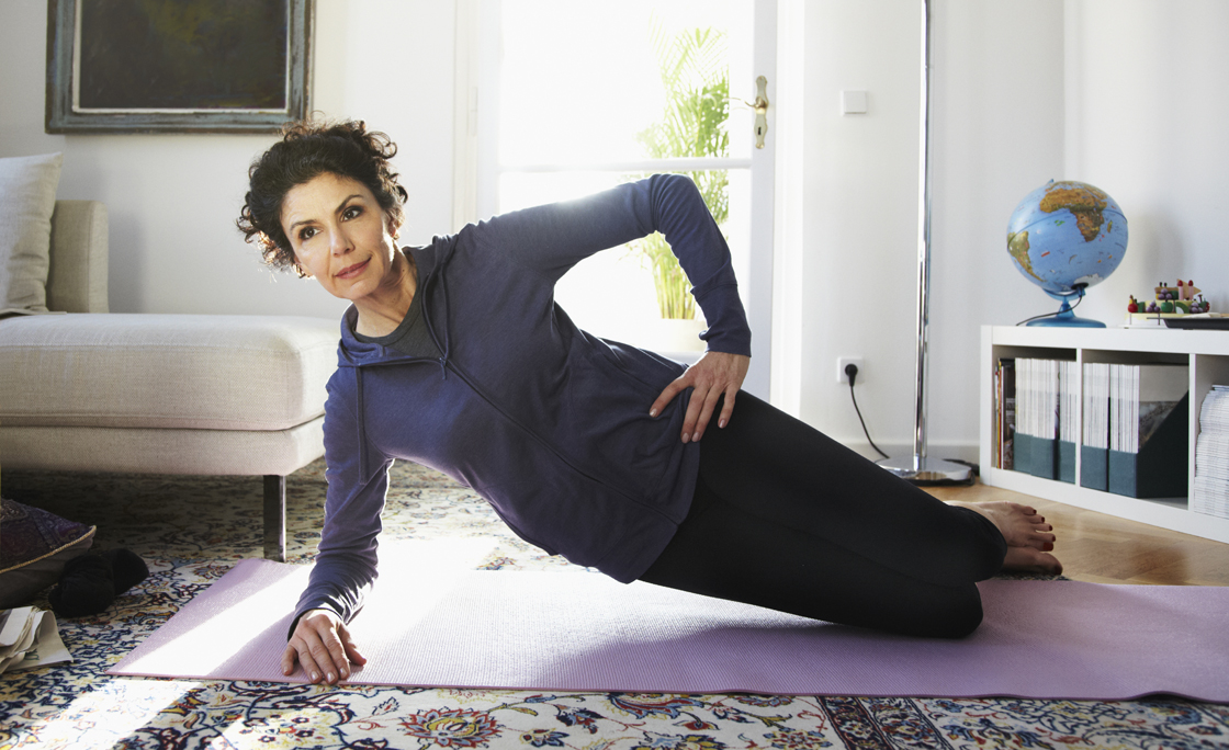 Mid-adult woman doing yoga at home