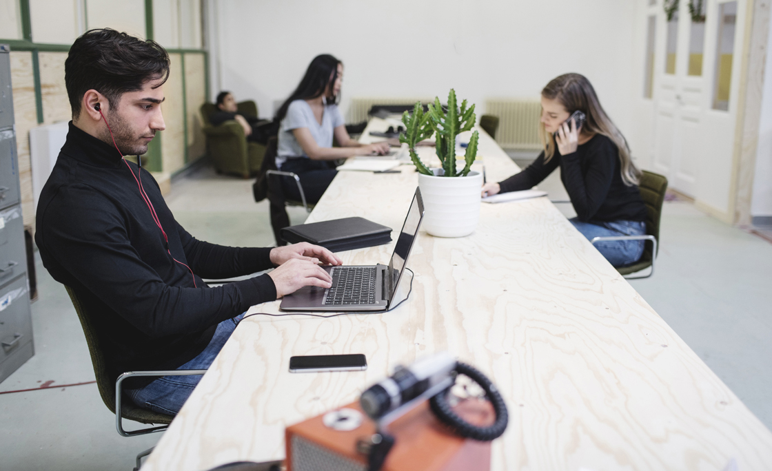 The entrepreneurs using laptops and smart phone at desk in creative office