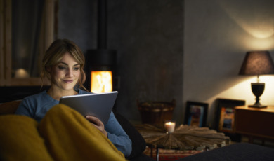Portrait of smiling woman with tablet relaxing on couch in the evening