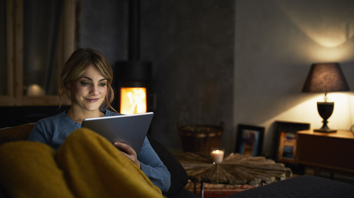 Portrait of smiling woman with tablet relaxing on couch in the evening