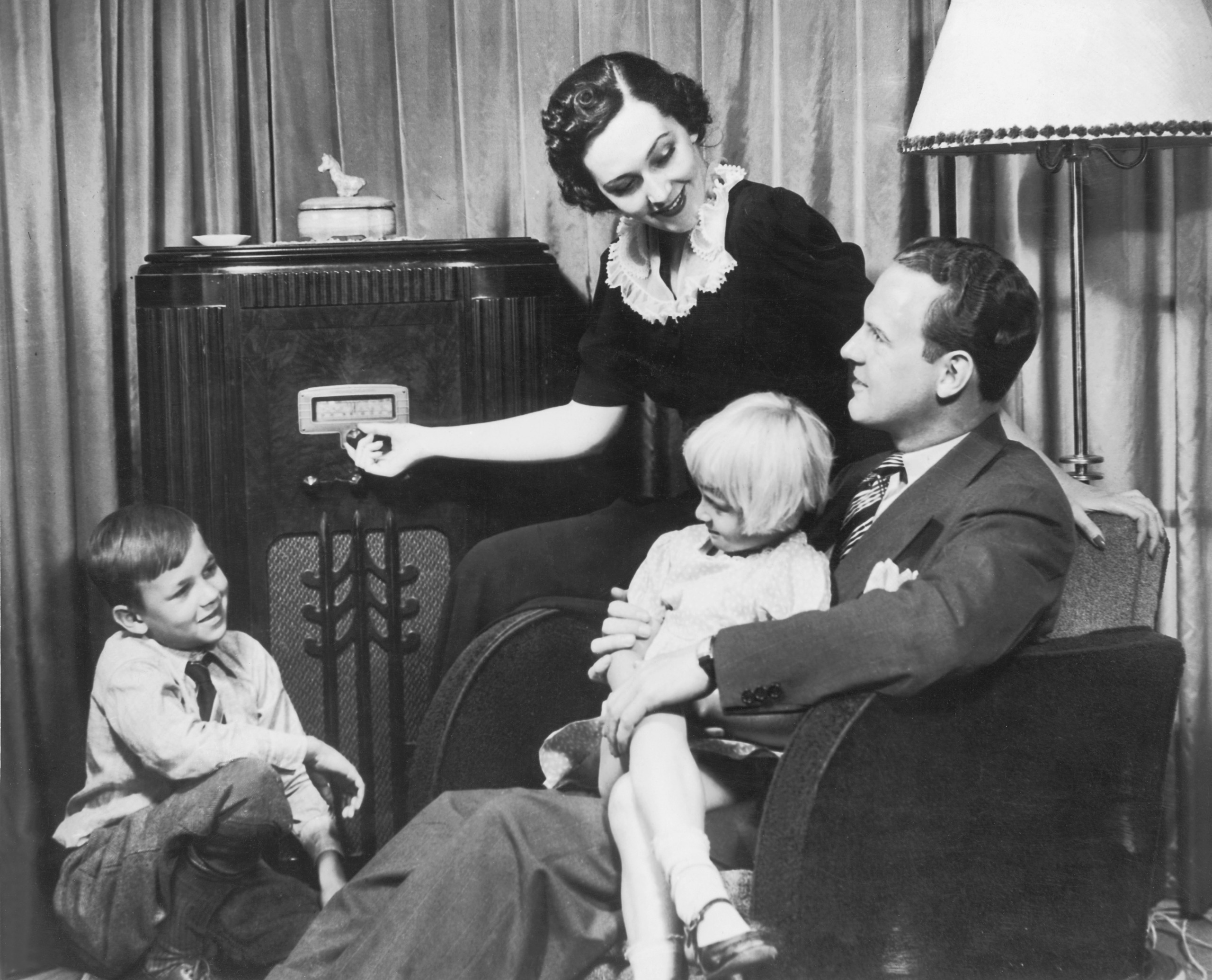 Parents and children (4-10) listening to radio set (B&W)