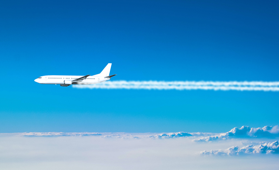 Airplane flying above the clouds leaving a smoke trail
