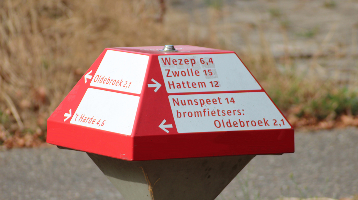 Direction sign with dutch city names in shape of mushroom in red and white colors for cyclist on the Veluwe in the Netherlands