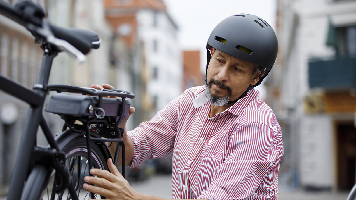 Senior man changing battery on electric bicycle