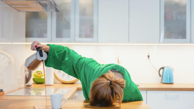 Tired Woman Trying To Drink Morning Coffee And Sleeping On The Table