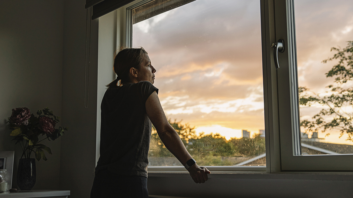Woman looking out of window at sunset