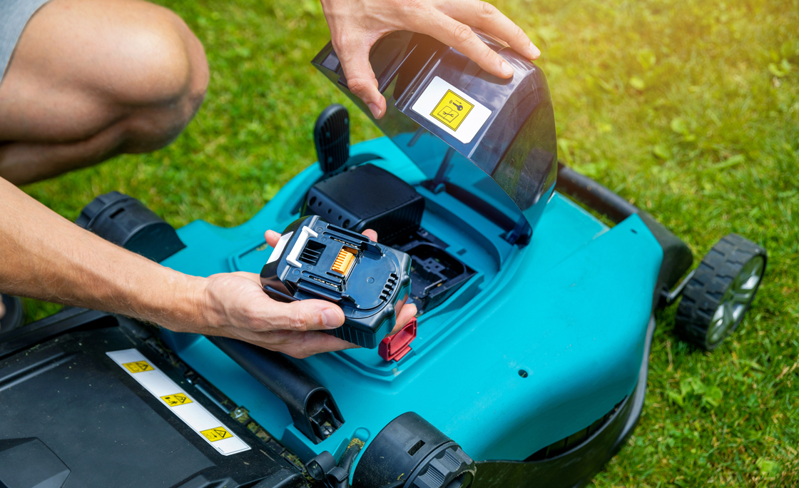man putting battery into electric cordless lawn mower