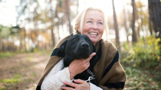 vrolijke vrouw met hond in bos
