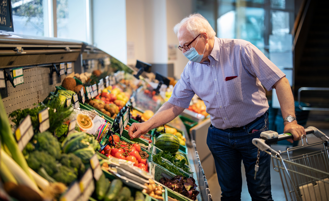 Senior man with face mask buying vegetables in grocery store