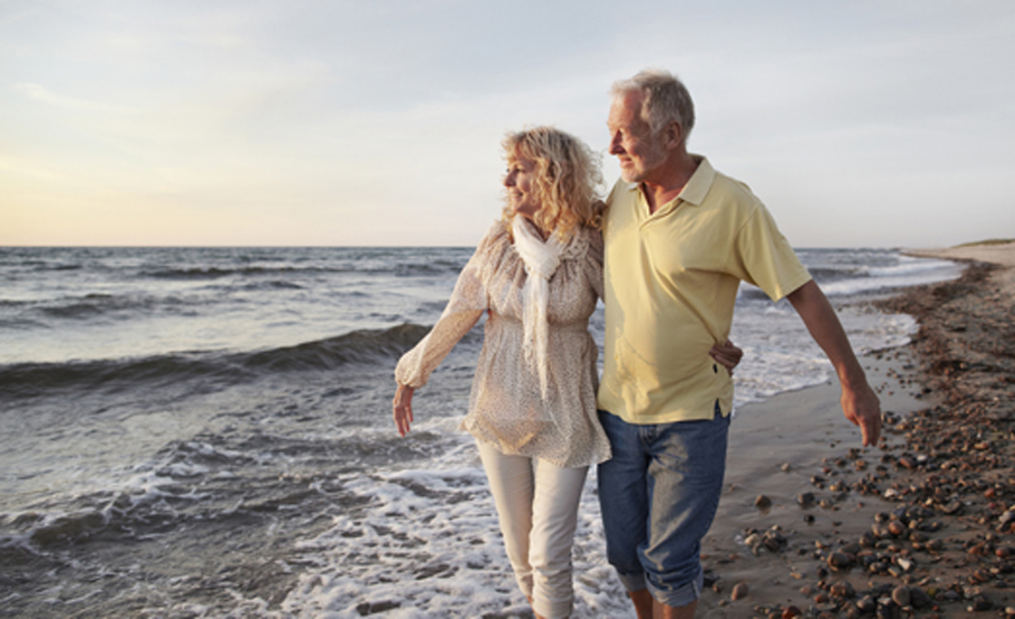 Mature couple paddling in sea looking at sunset