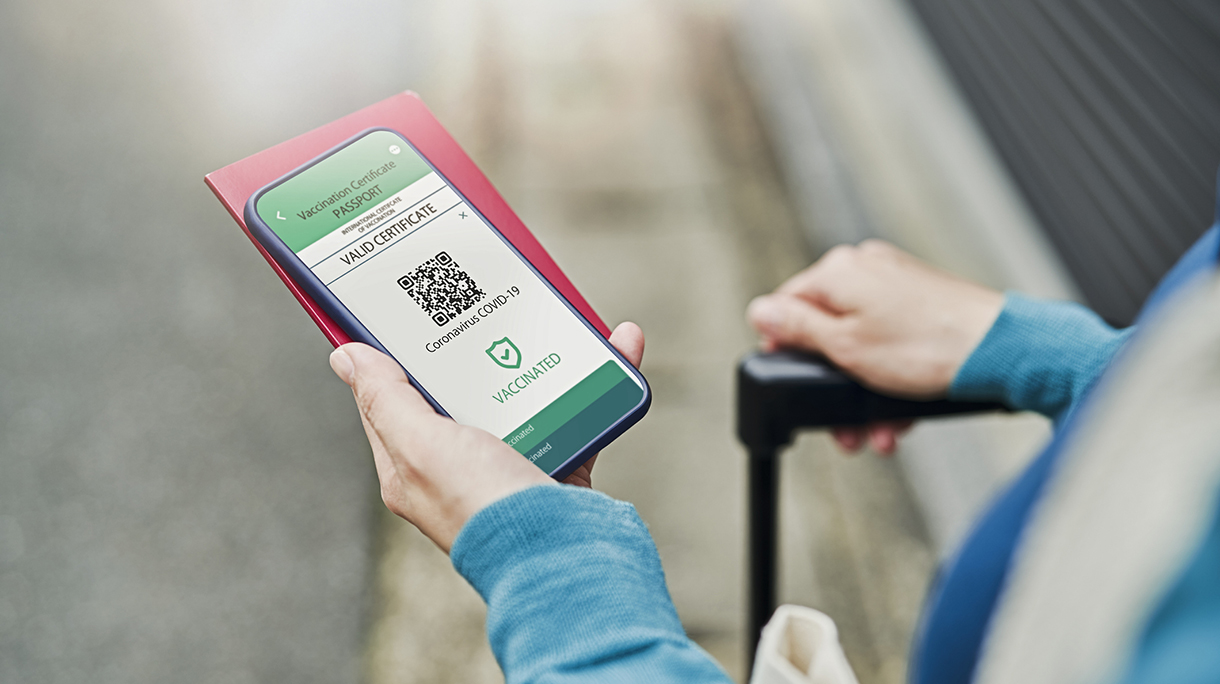 Mid adult woman using a Digital vaccine passport with smart phone in outdoor.