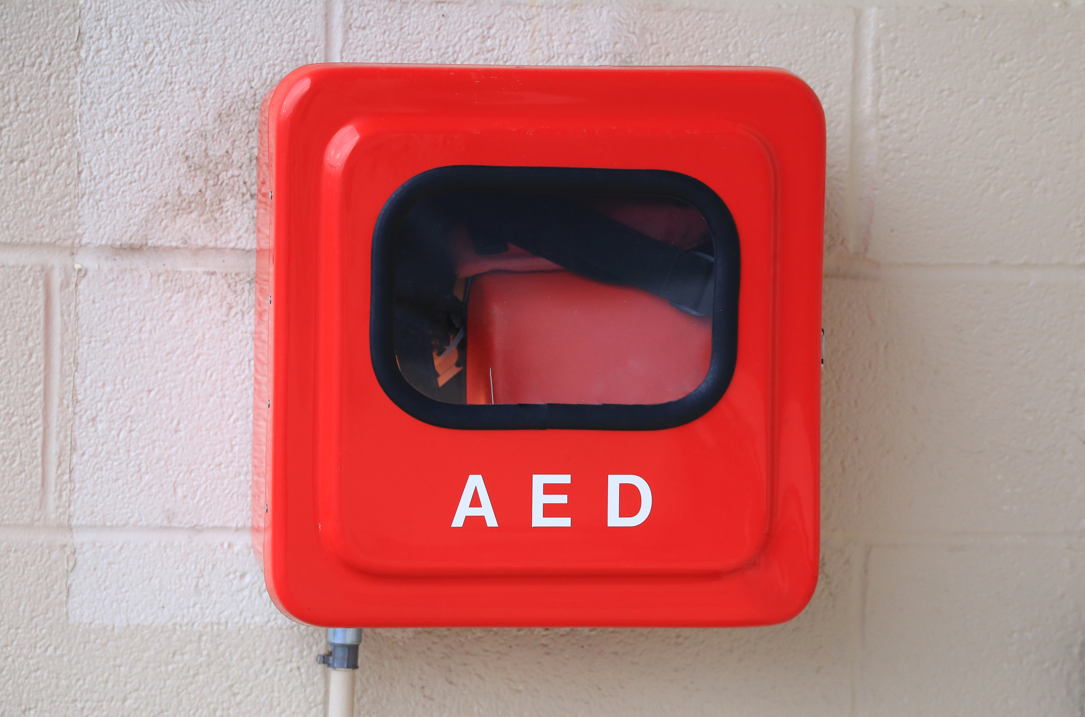 Automated External Defibrillator (AED) for heart attack emergency is mounted on a wall in a red box
