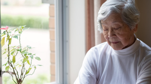 Lonely, Senior Woman Sitting by Window with Eyes Closed