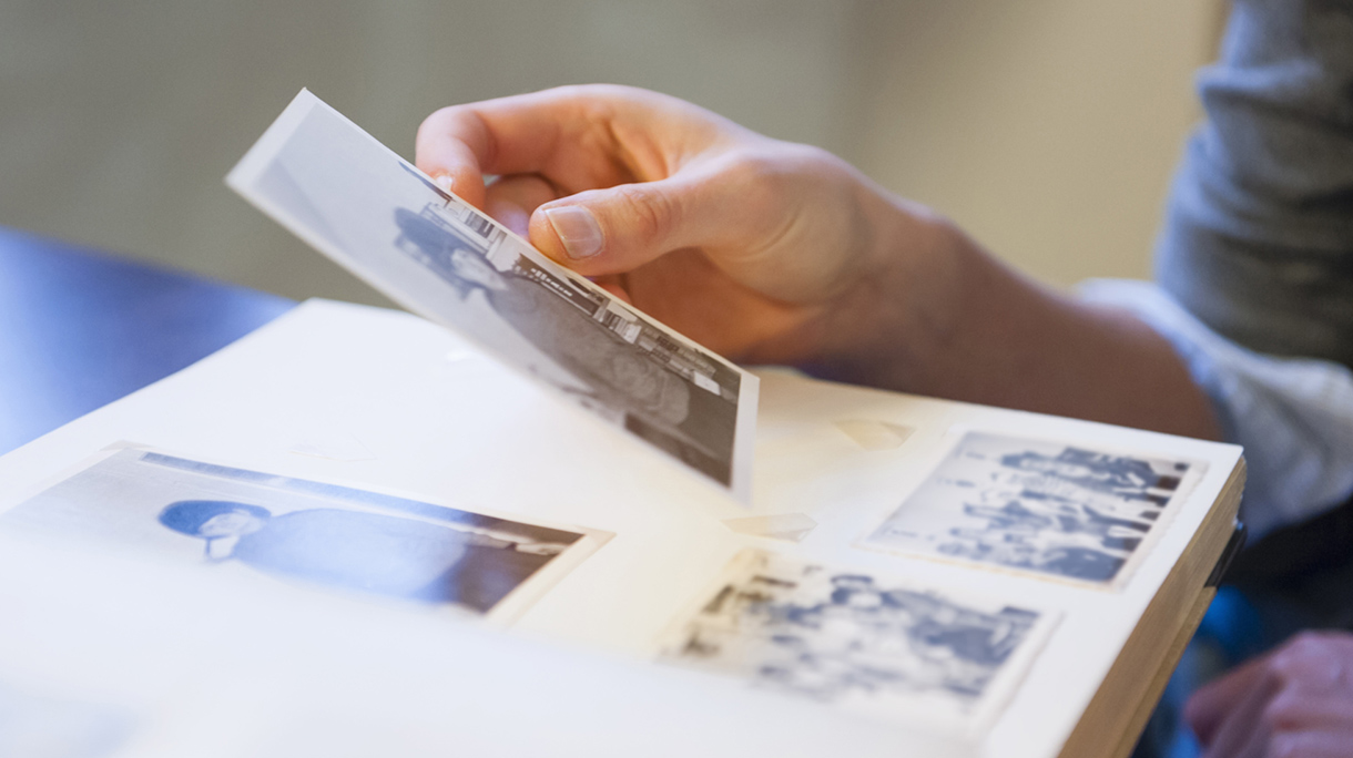 Cropped hand of mid adult woman holding photograph at home