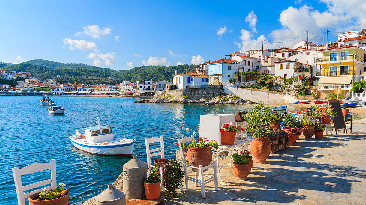 Flower pots on and view of fishing boats anchoring in Kokkari bay, Samos island, Greece